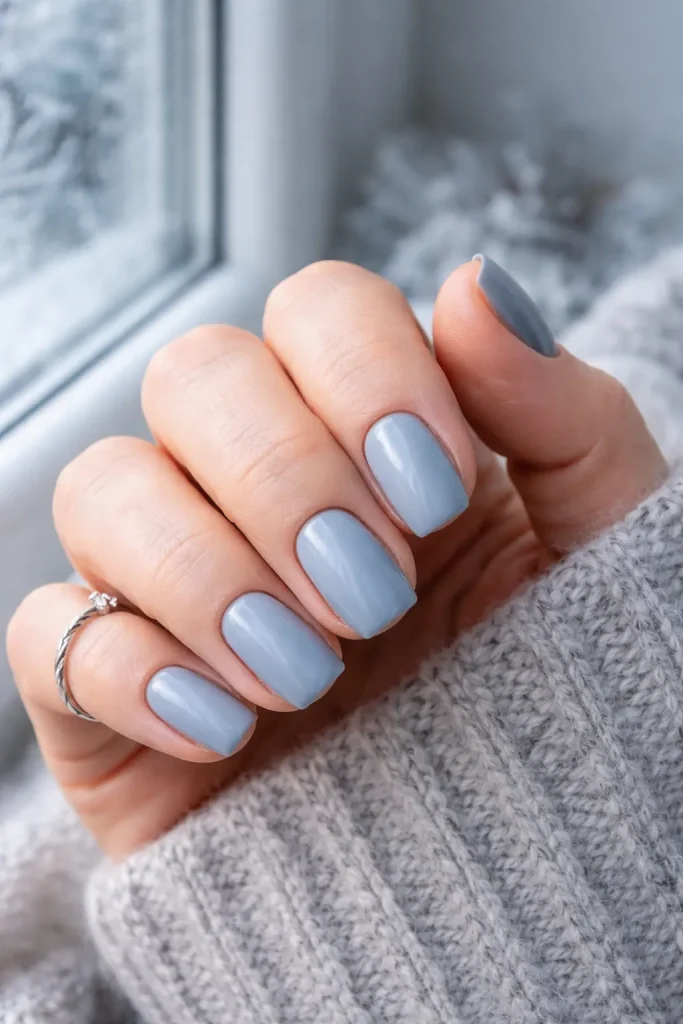 Soft dusty blue nail polish on mature hands in cool natural light