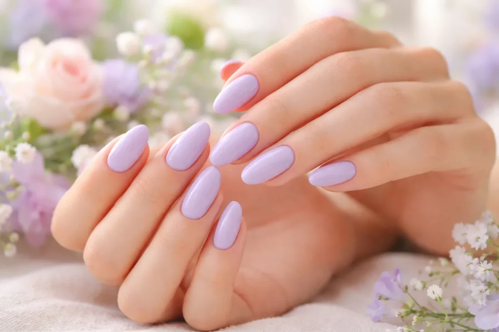 Delicate light lavender nails against a soft-focus floral background.