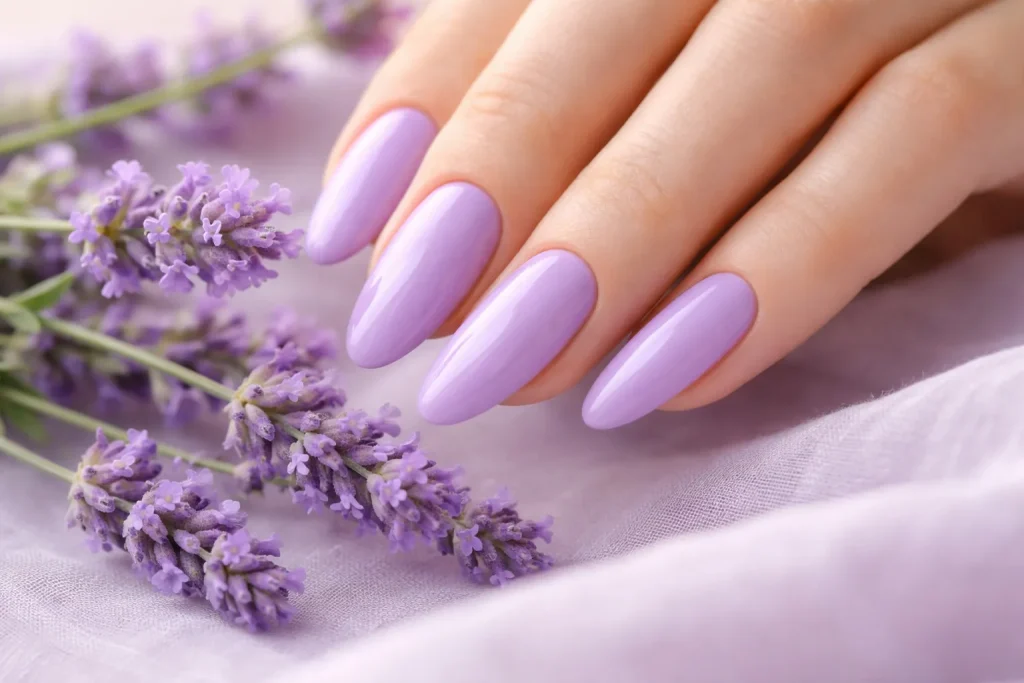 Elegant lavender purple nail polish on long almond nails next to fresh lavender flowers.