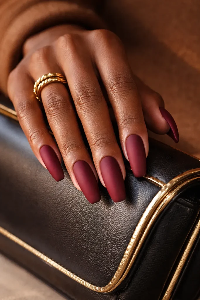 Matte burgundy nails with a velvety texture on a hand with rich mahogany skin tones.