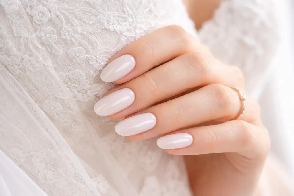 Elegant milky white manicure against a white lace wedding gown