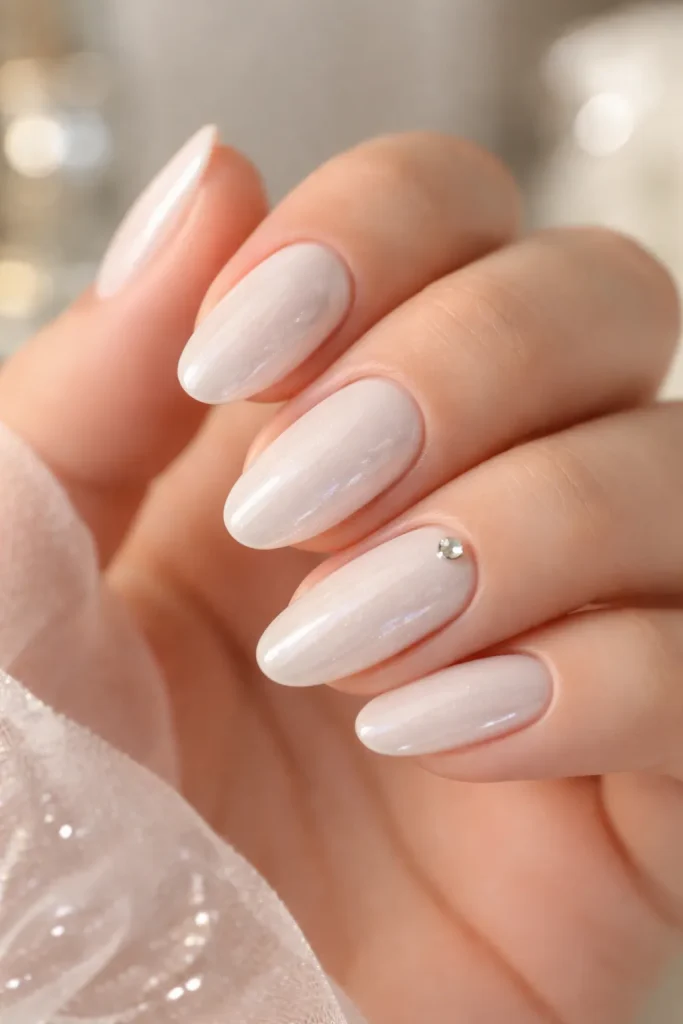 Pearl white nails with a single small rhinestone accent for a wedding
