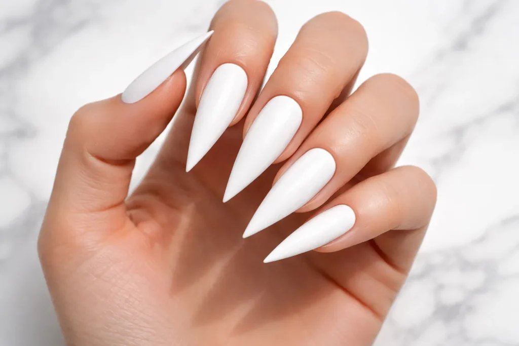 Crisp bright white stiletto nails on a marble surface in bright lighting