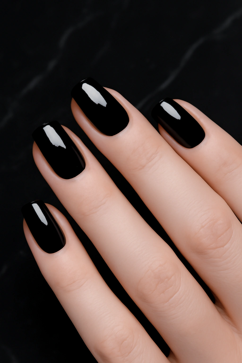 Glossy black nail polish on fair skin creating a high contrast dramatic look