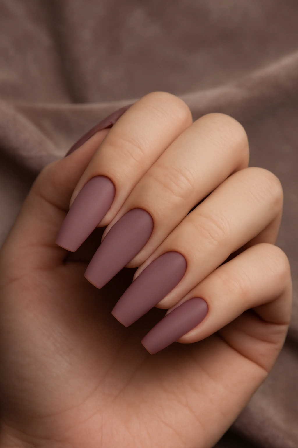 Matte mauve coffin shaped nails on a fuller hand showing the flat tip and tapered sides.