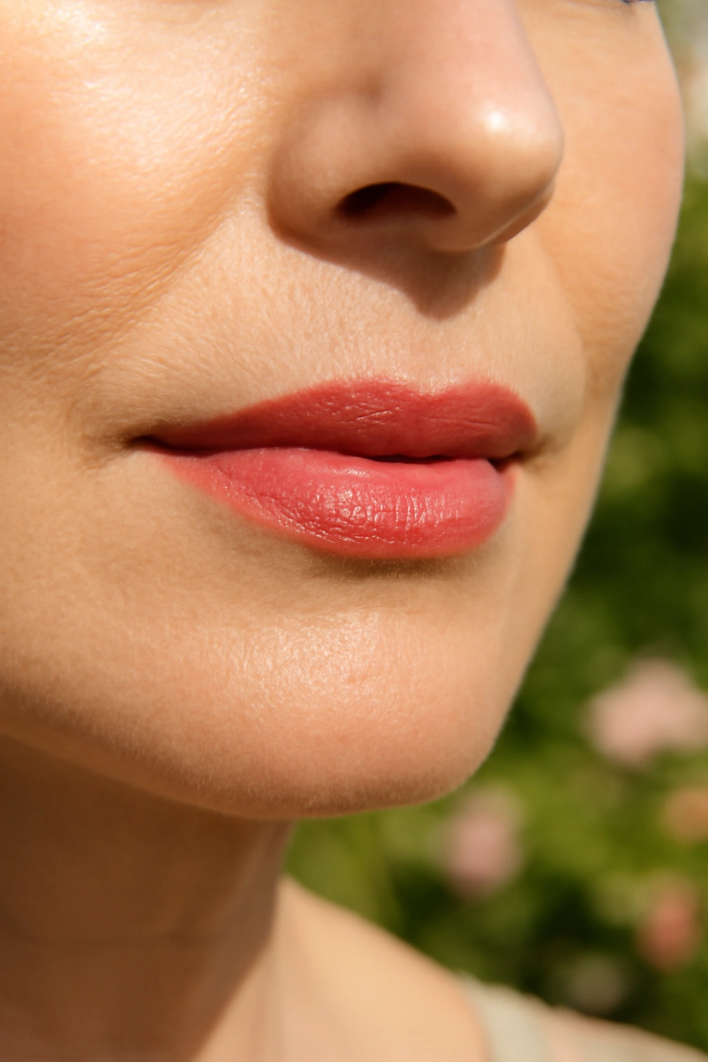 Close up of coral blush lipstick on a smiling mature woman at a summer wedding