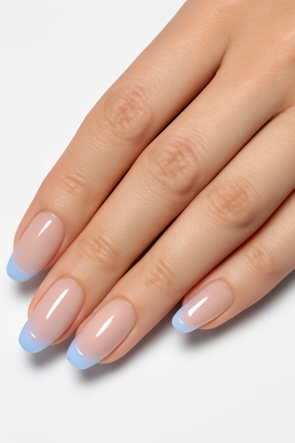 Modern French manicure with sheer base and light blue colored tips on fair skin