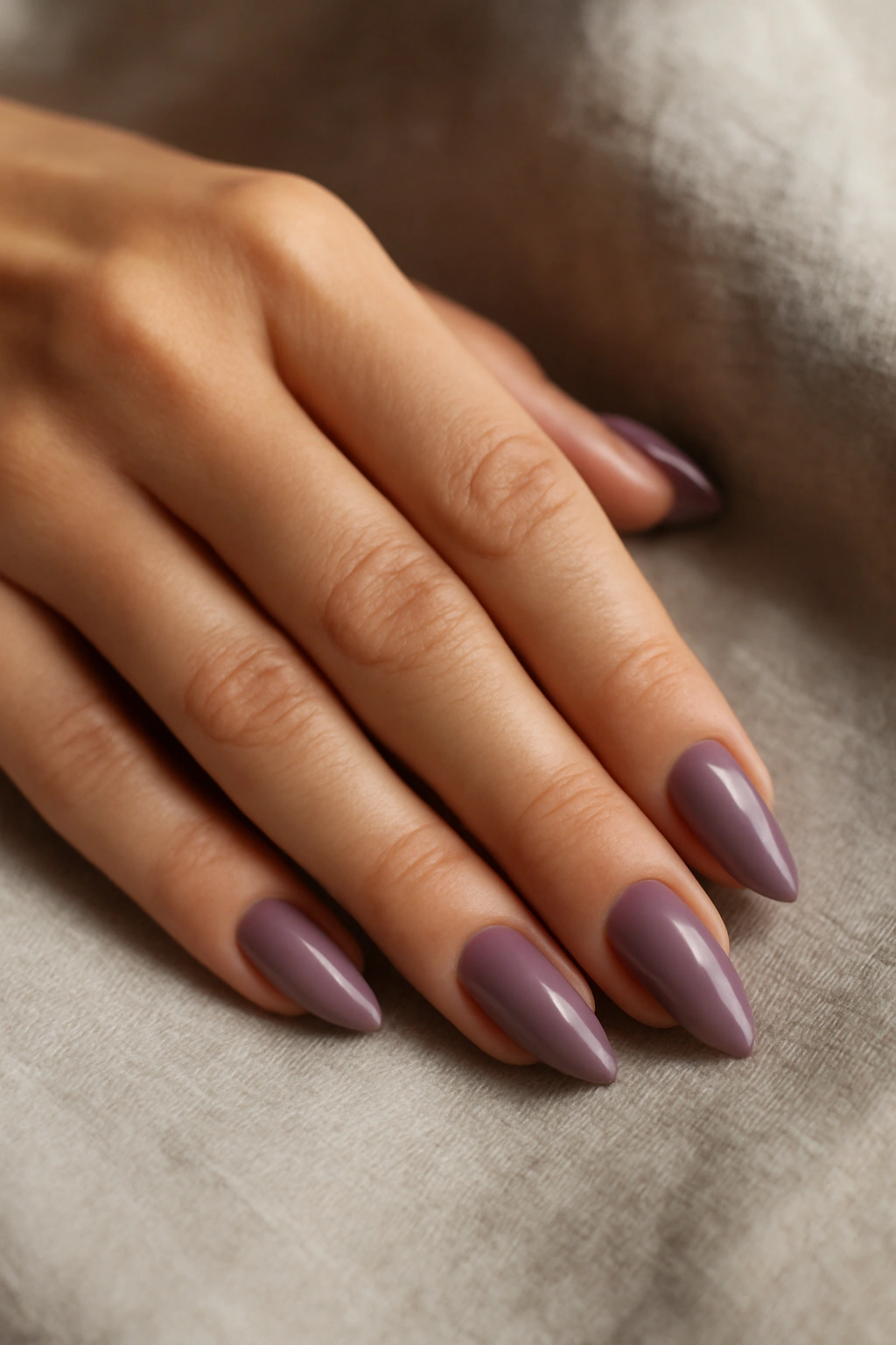 Sophisticated muted mauve nails on a hand resting on linen.