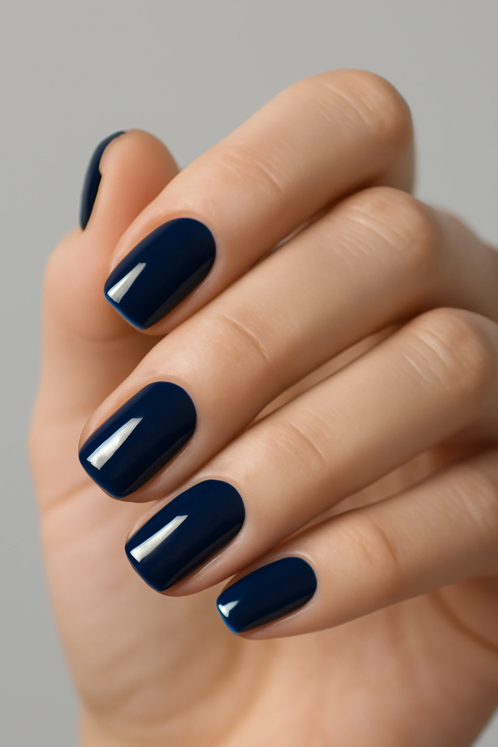 Short sophisticated nails with a high-shine navy blue polish