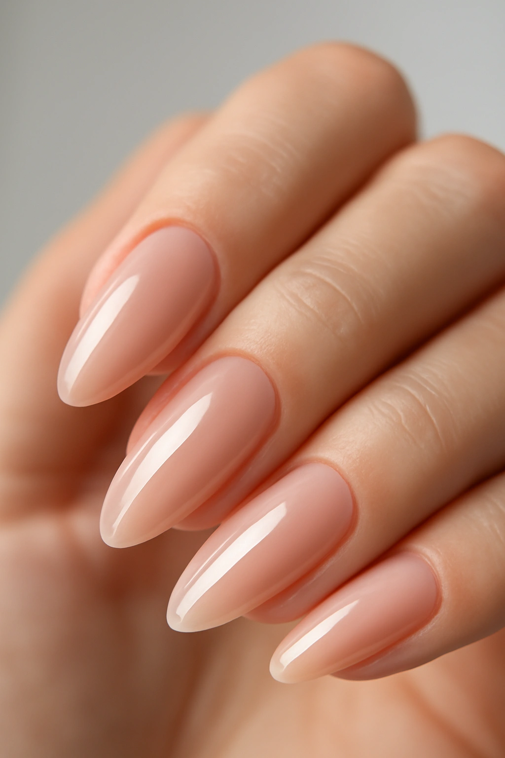 Close-up of nude pink almond nails with a high-gloss topcoat