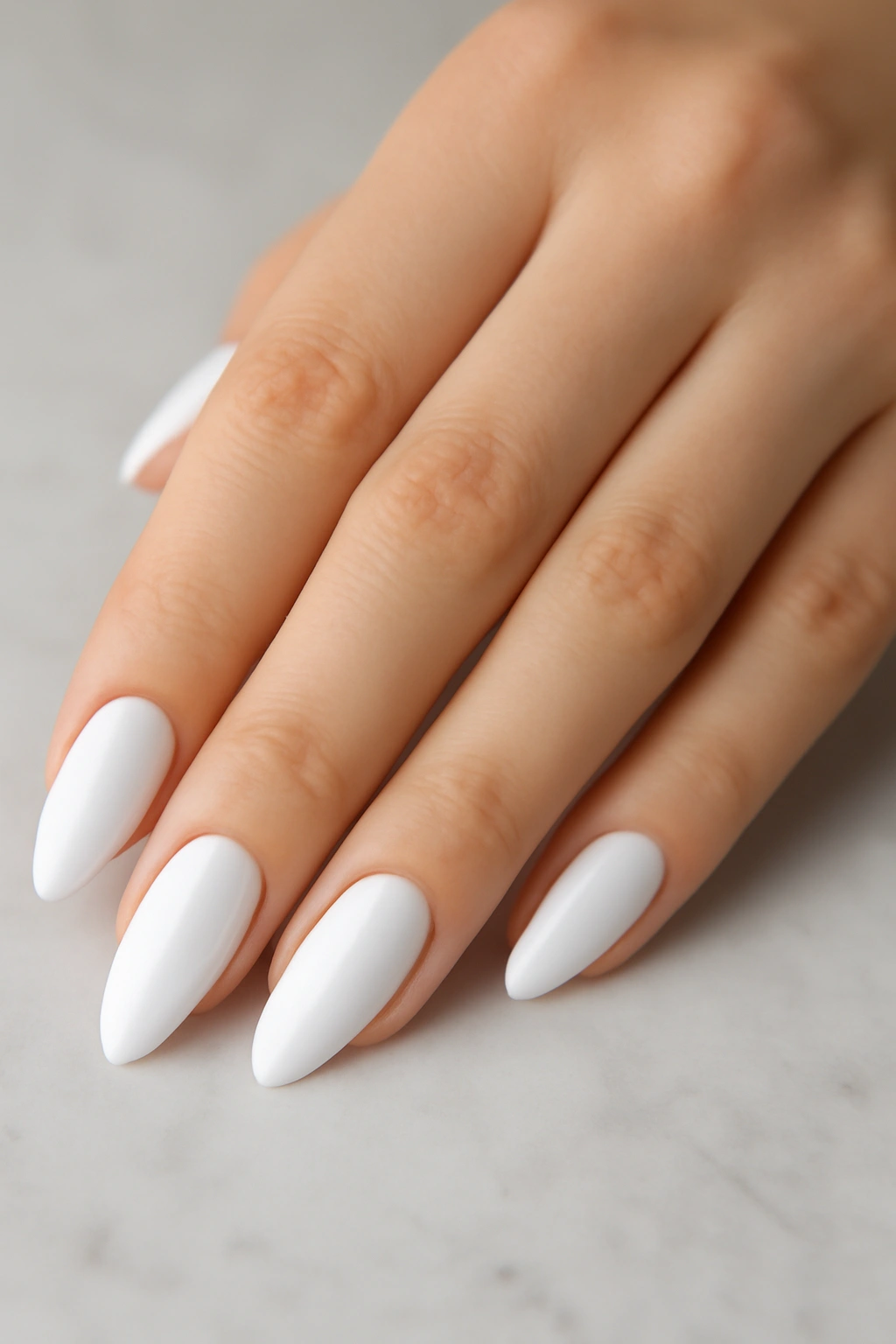 Manicured crisp white nails on fair skin resting on a marble surface
