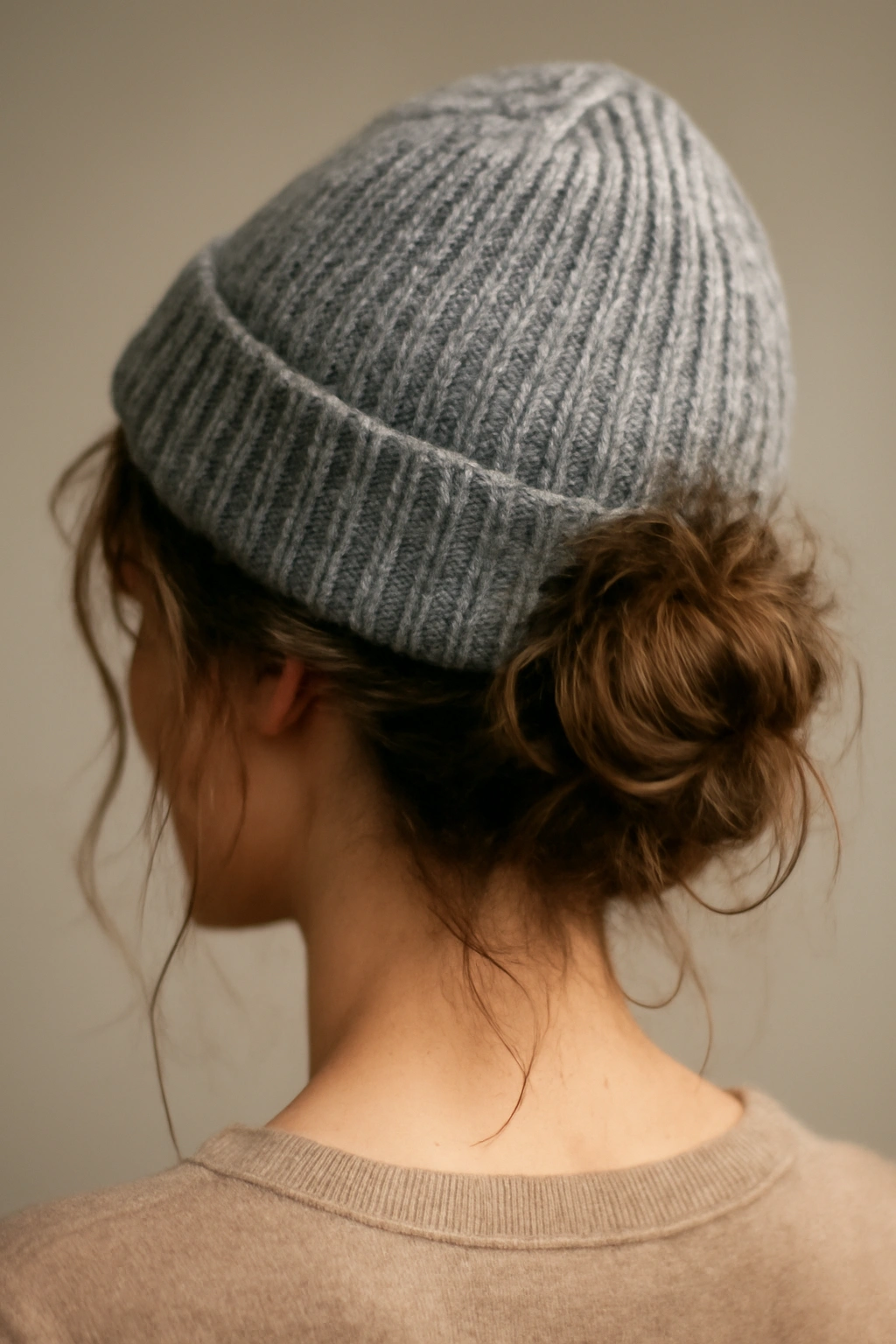 Textured messy bun with beanie viewed close-up highlighting loose strands